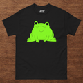 Black t-shirt with a green frog graphic on a wooden surface