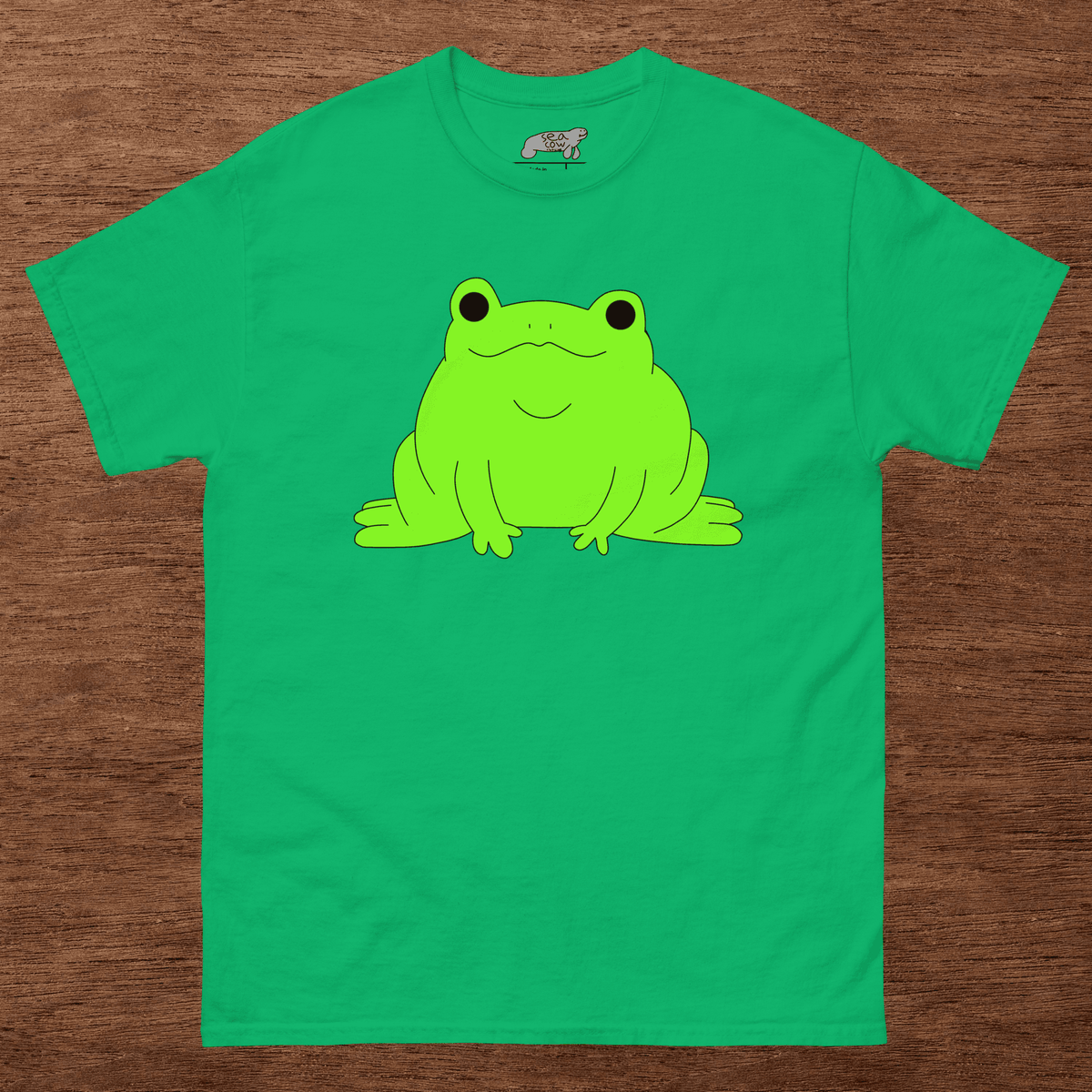 Green t-shirt with a frog graphic on a wooden surface
