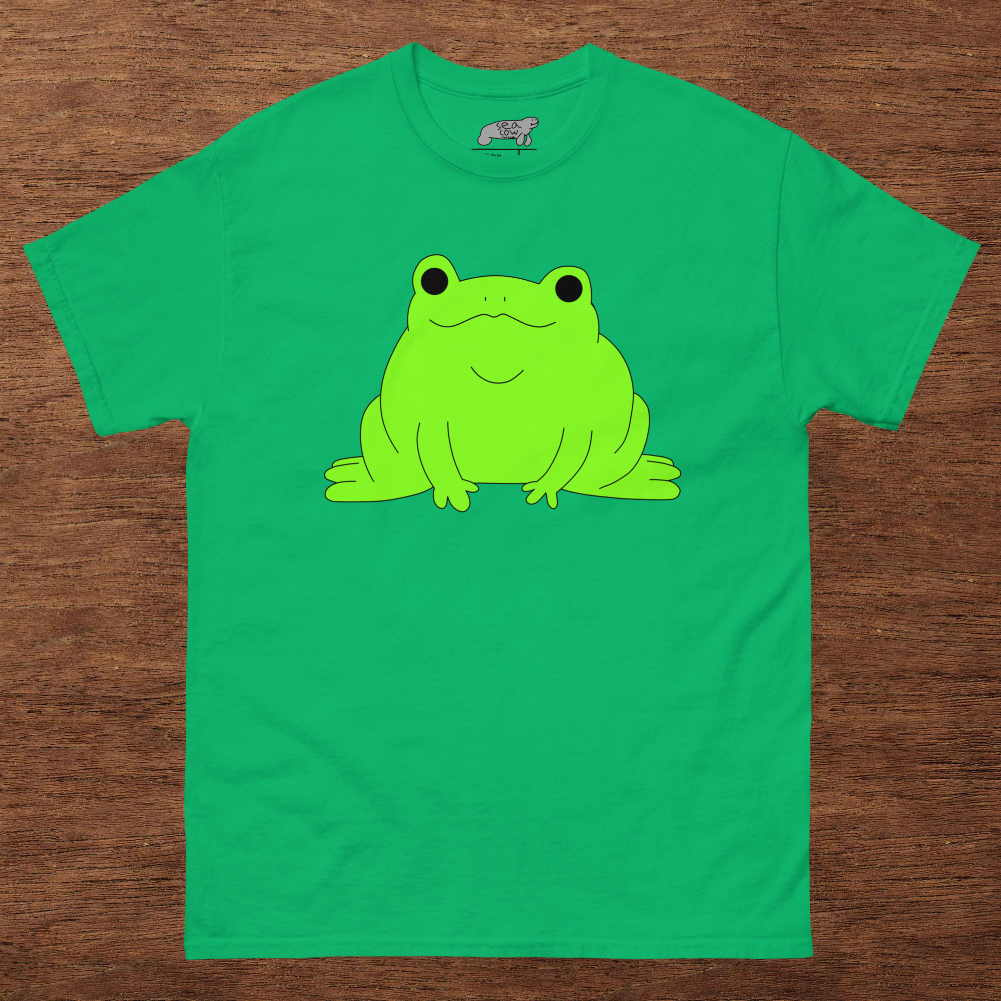 Green t-shirt with a frog graphic on a wooden surface