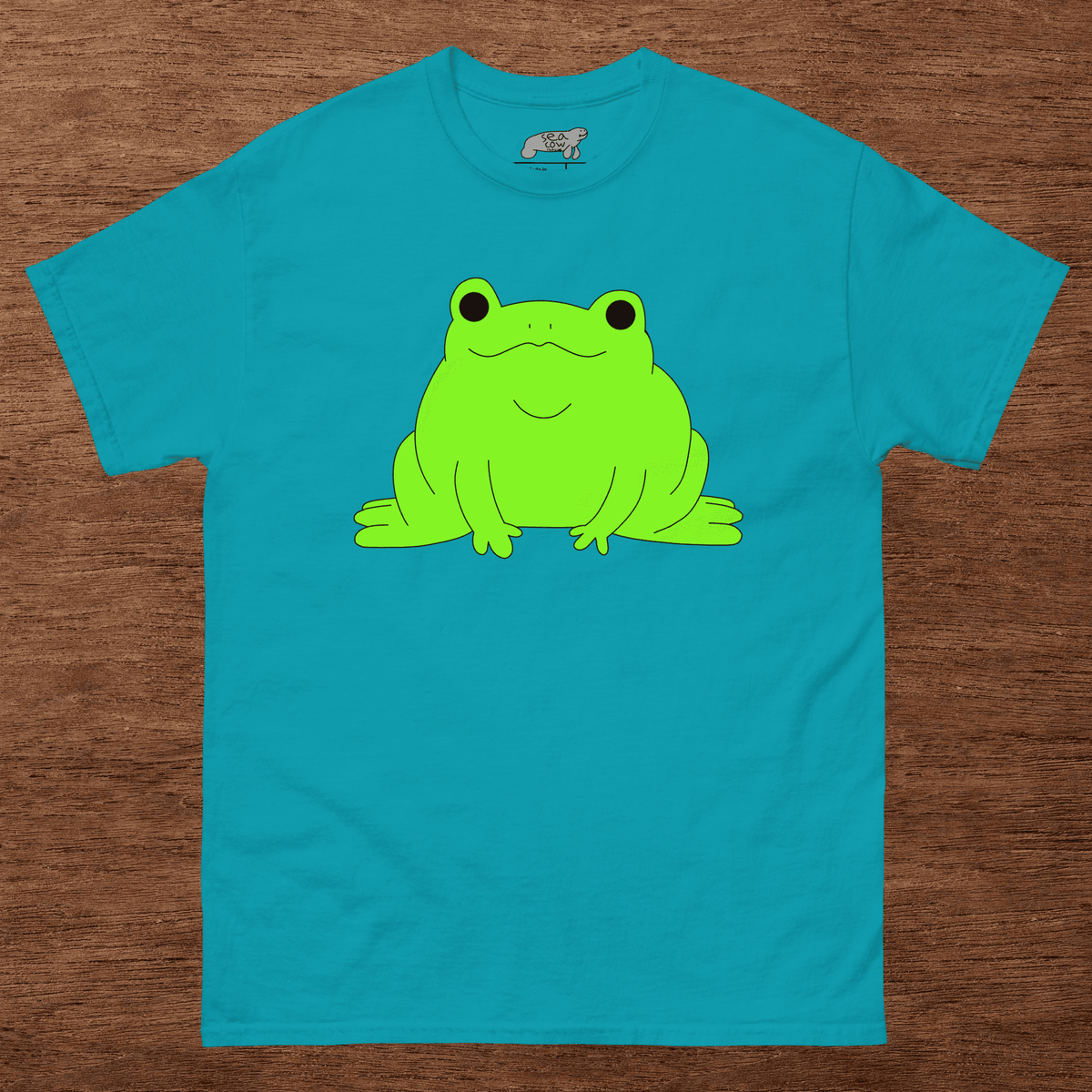 Blue t-shirt with a green frog graphic on a wooden surface