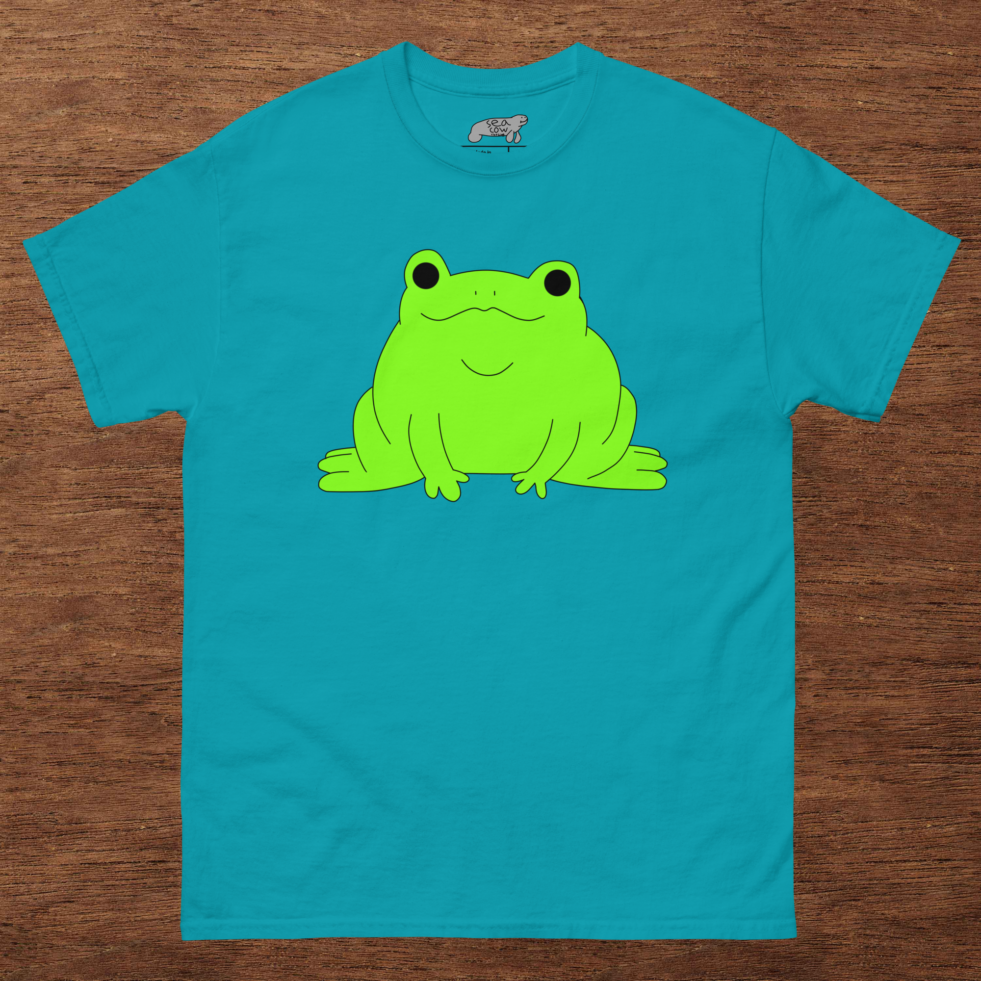 Blue t-shirt with a green frog graphic on a wooden surface